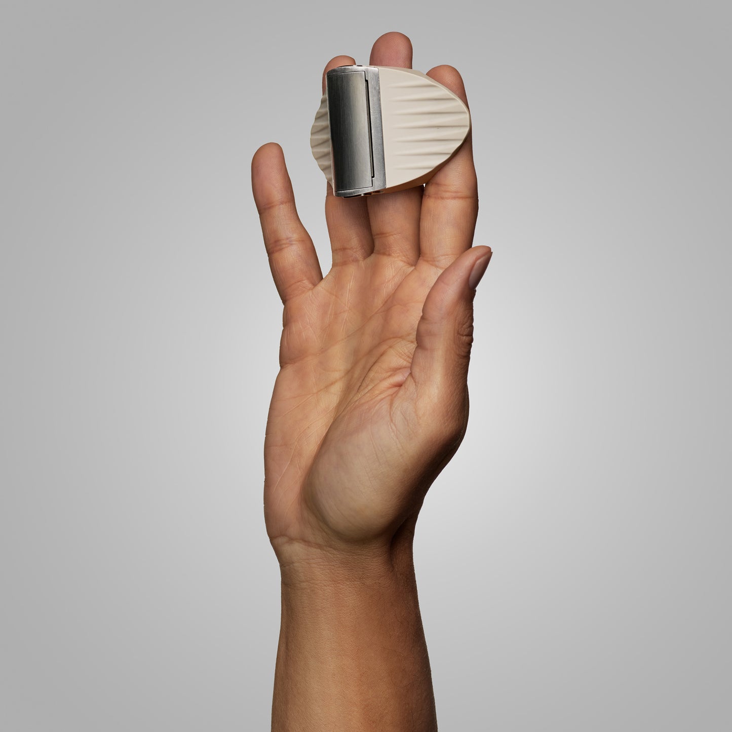 Hand holding CAVEX head shaver against a gray background