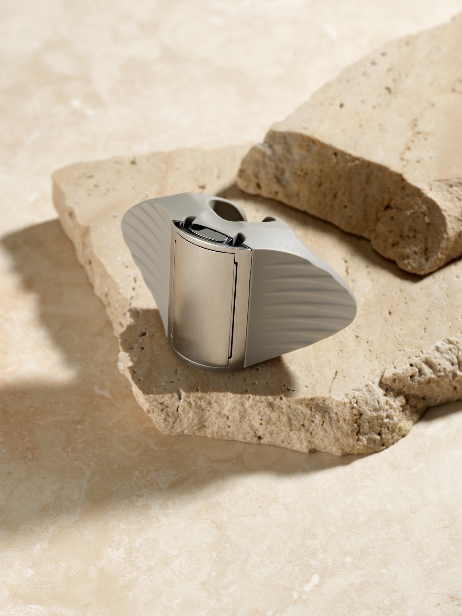 Silver electronic device on a stone surface with a natural light background